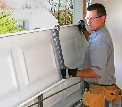 Technician replacing garage door panel in Meridian